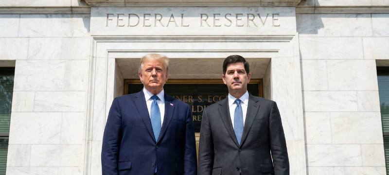 Ilustración que representa el impacto de la transición en la Reserva Federal sobre los mercados financieros globales. Kevin Warsh, nominado por Donald Trump como próximo presidente de la Fed, se encuentra en el centro de un debate político y económico. La imagen podría incluir símbolos del dólar y la Reserva Federal, así como gráficos que muestran la volatilidad del mercado. También podría haber elementos que reflejen el impacto en Latinoamérica, como monedas regionales y gráficos de commodities.